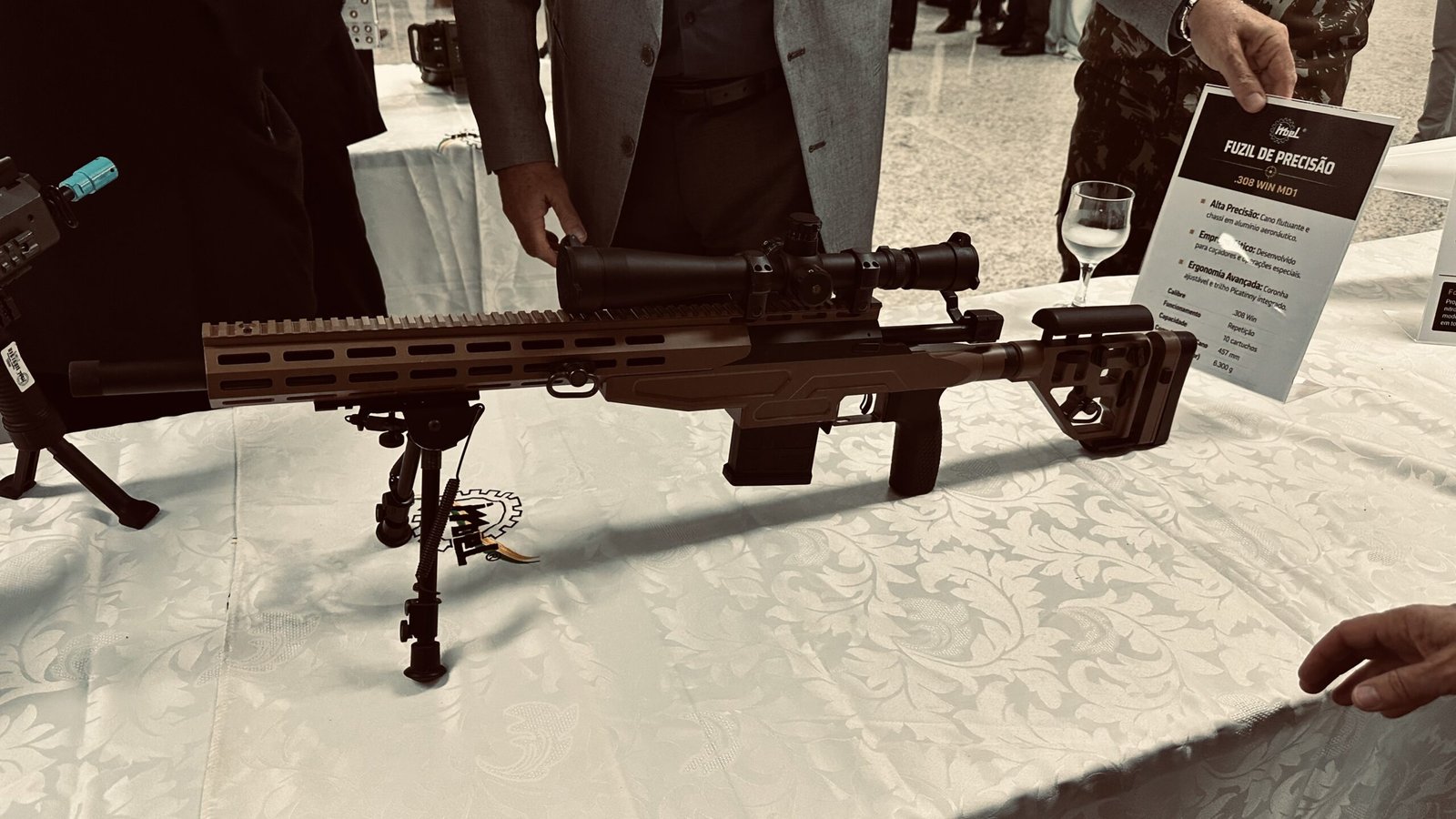 Fuzil de Precisão .308 WIN MD1 — exposição IMBEL na SEF/QGEx, Brasília, 1º de julho de 2026. Ao fundo, ficha técnica oficial. Crédito: Acervo Reaction News.